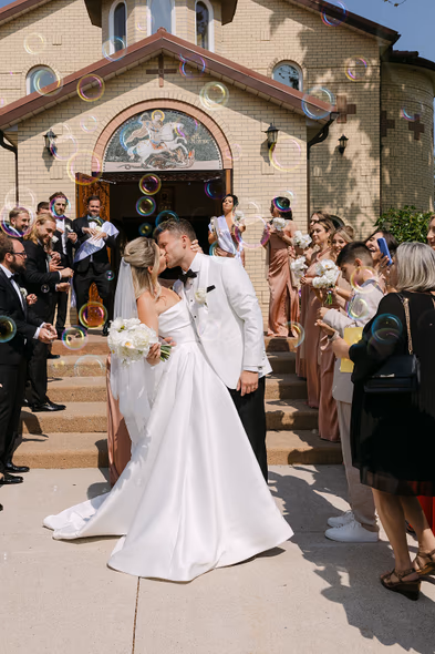 Chateau des Charmes wedding photos of couple kissing outside church with guests