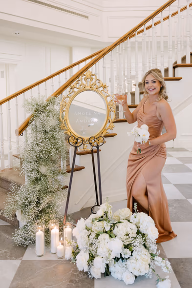 Bridesmaid posing by floral welcome sign at Chateau des Charmes wedding
