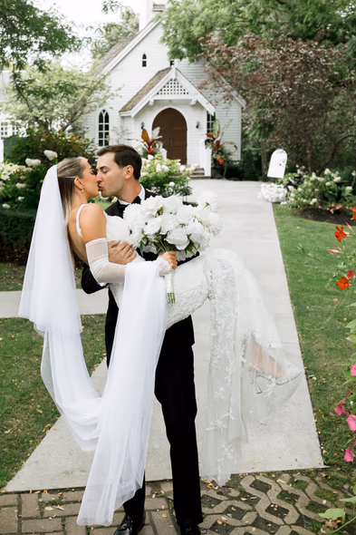 bride and groom kissing in front of Doctor’s House chapel