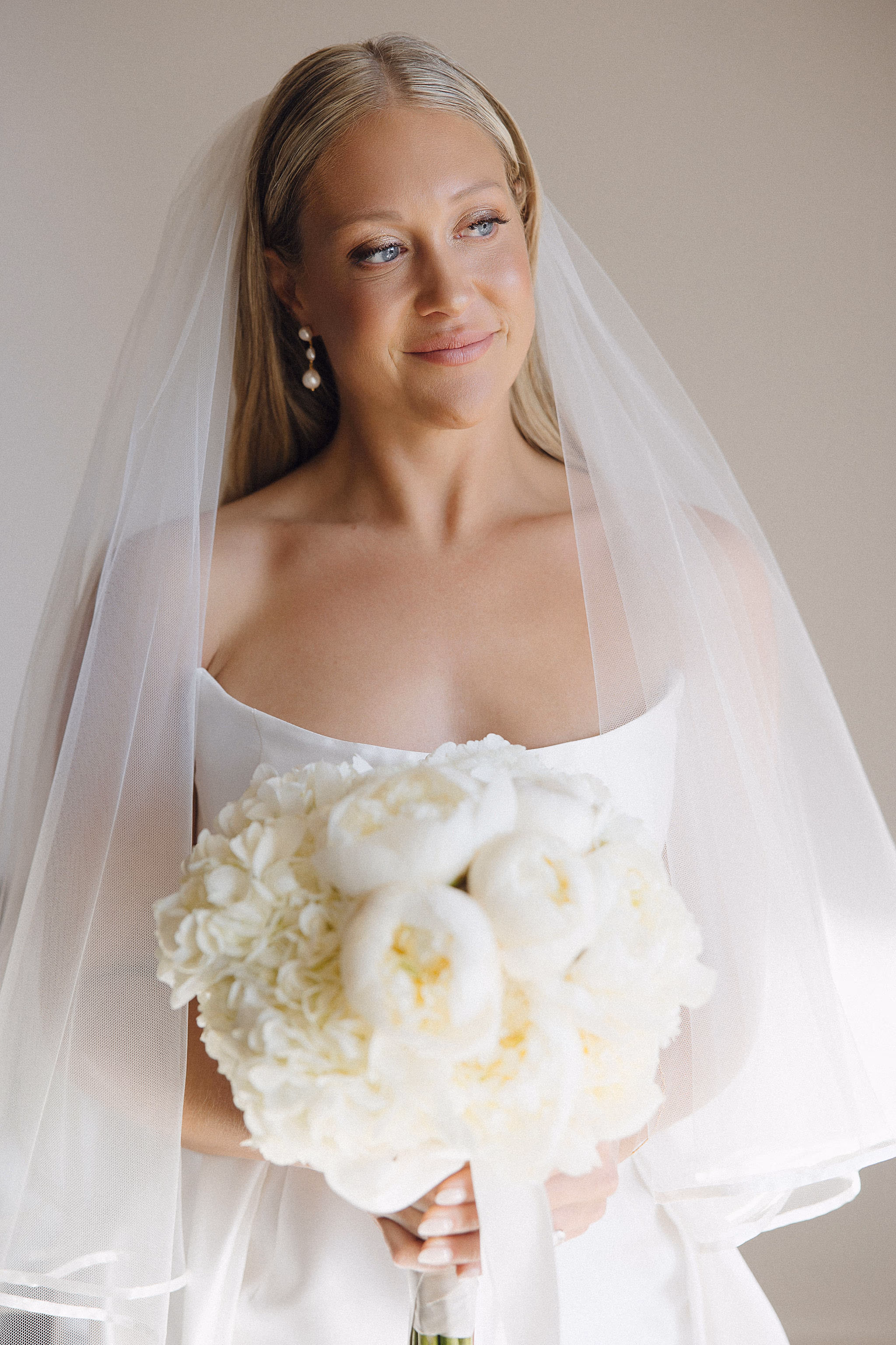 Smiling bride holding a lush bouquet under her veil at Lido House
