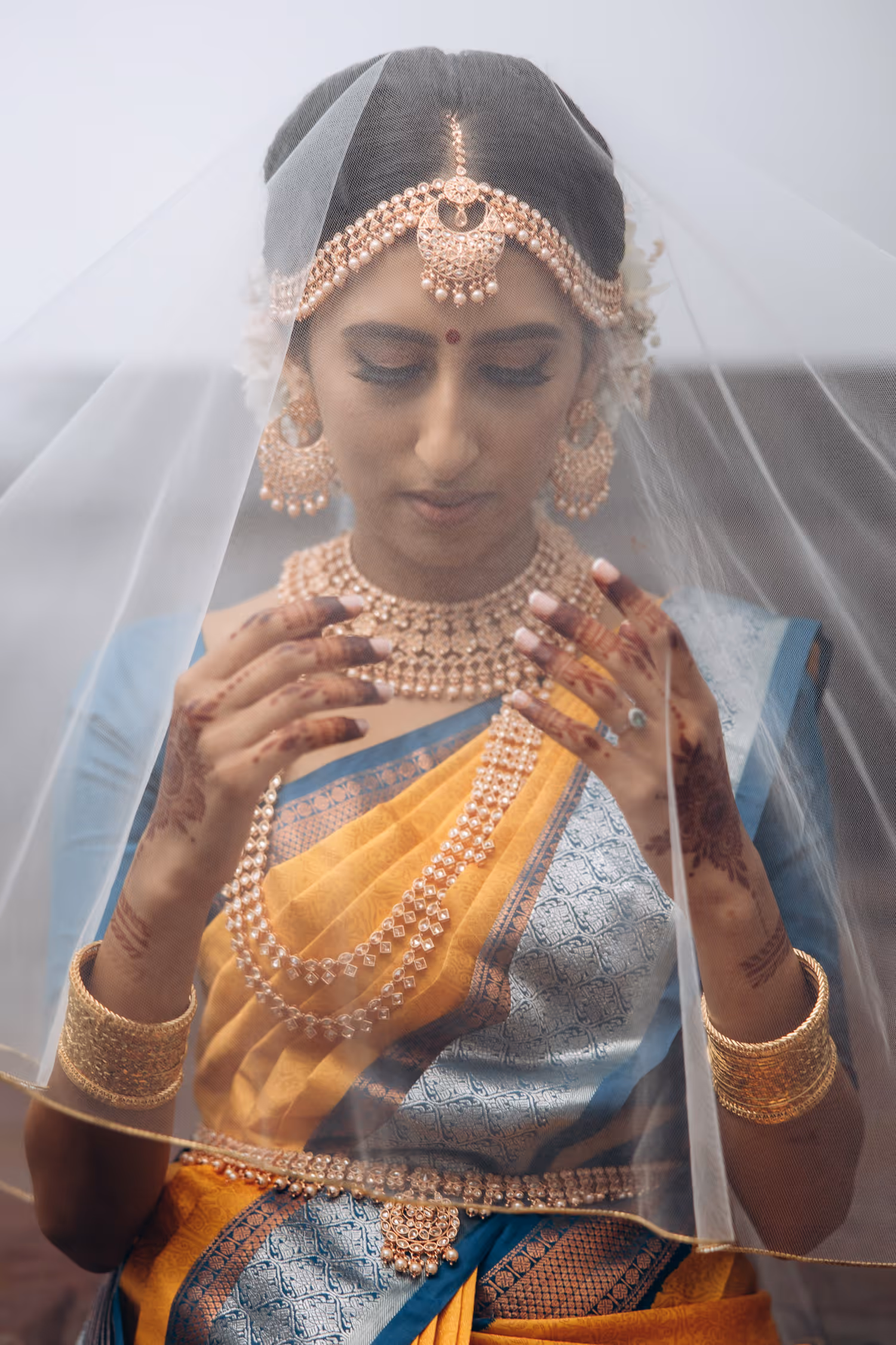 Bride wearing traditional blue saree under veil before Tamil wedding ceremony