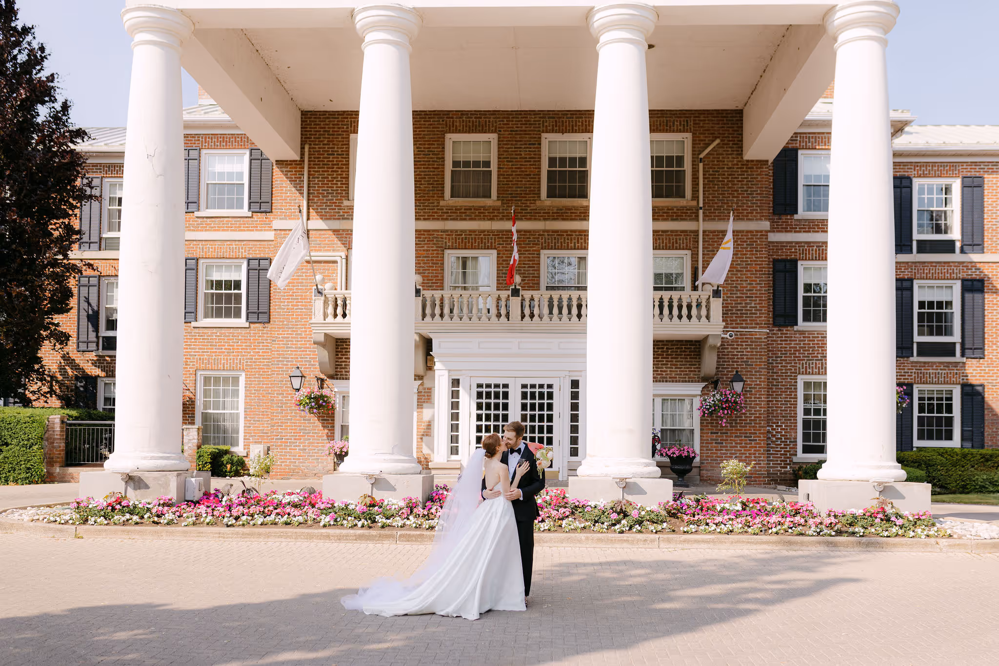 candid couple's portrait in front of Queen’s Landing Hotel in Niagara-on-the-Lake — Astora Studio